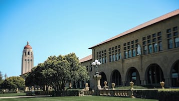 A building with a clock tower, arched windows, and a well-maintained lawn.
