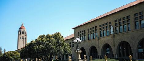 A building with a clock tower, arched windows, and a well-maintained lawn.