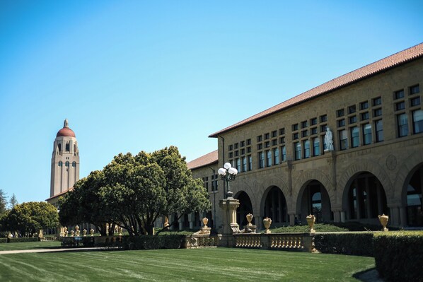 A building with a clock tower, arched windows, and a well-maintained lawn.