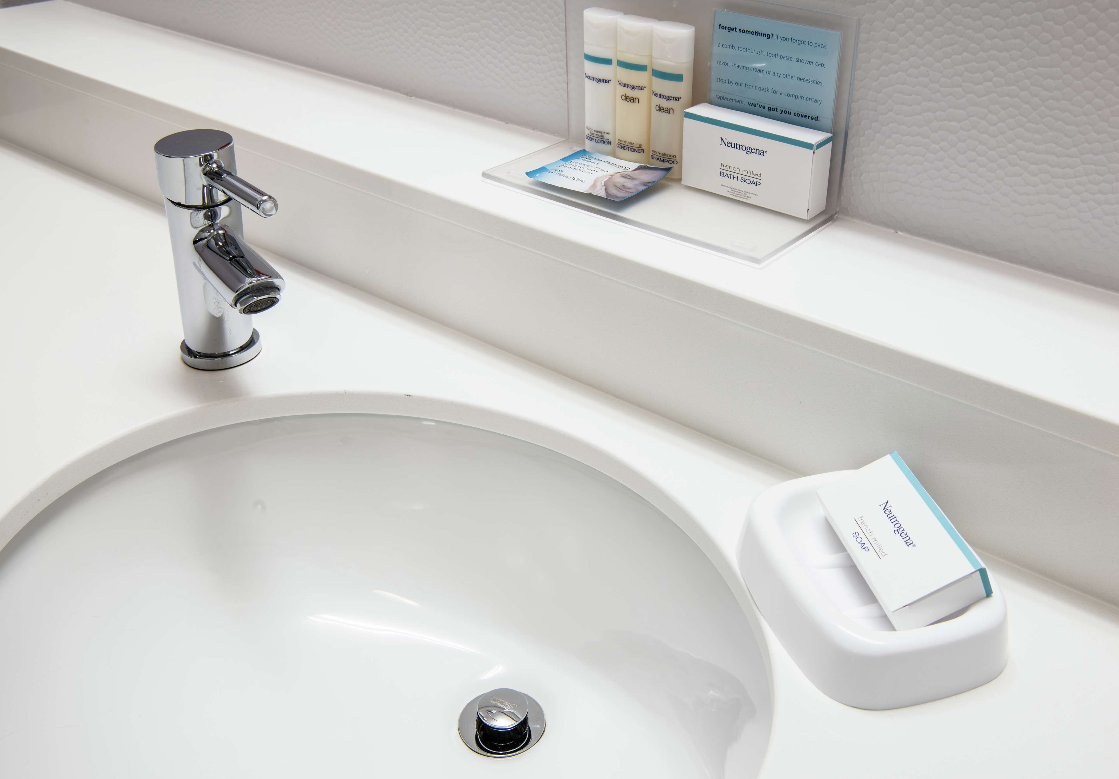 A white bathroom sink with a chrome faucet, a soap dispenser, and a box of Neutrogena bath soap on the countertop.