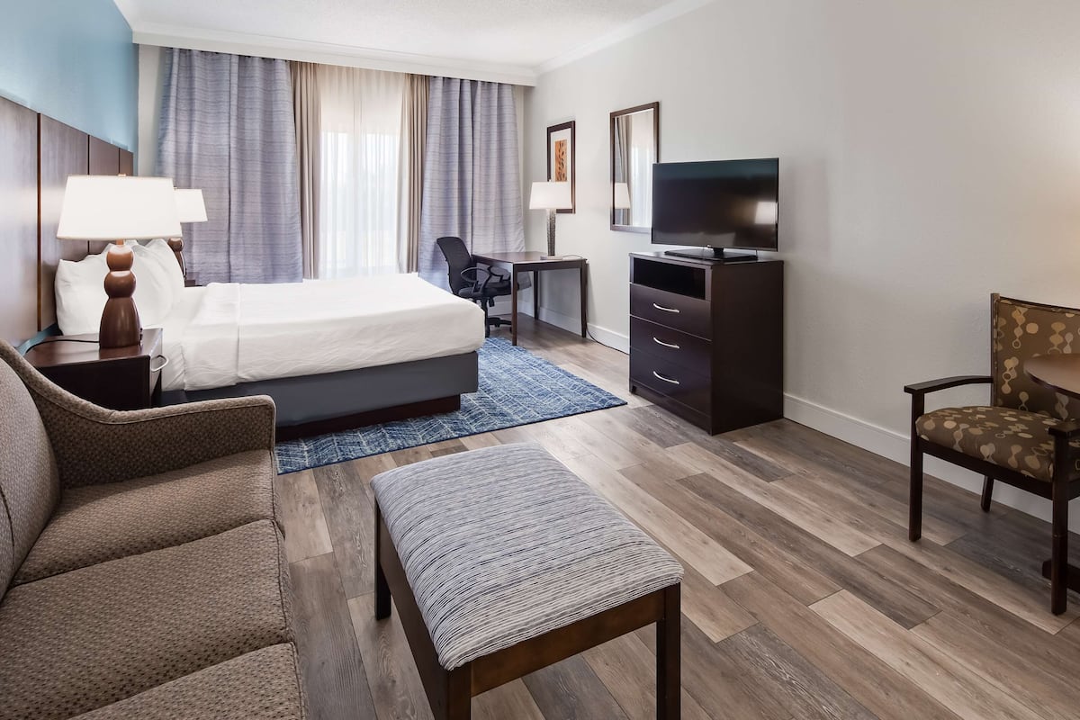 Une chambre d’hôtel équipée d’un lit, d’un bureau, d’une télévision et d’un coin salon.