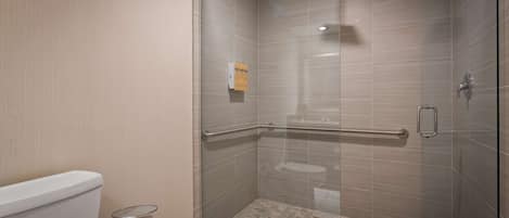 Une douche moderne dotée d’une paroi en verre, d’une barre d’appui et d’un sol carrelé.