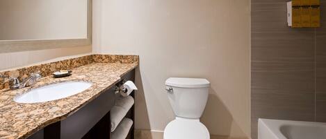 A bathroom with a granite countertop sink, a toilet, and a bathtub.