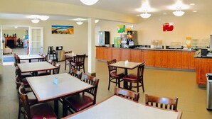 A restaurant with multiple tables and chairs, a counter with a beverage station, and a view of the dining area.