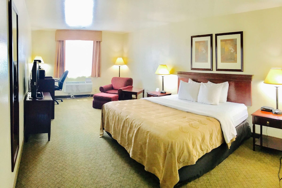 Ein Hotelzimmer mit Bett, Schreibtisch, Stuhl und zwei Lampen.