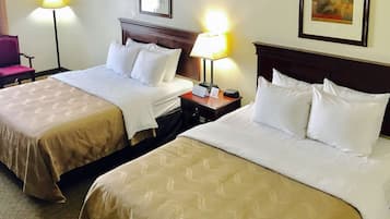 Habitación de hotel con dos camas, cada una con cabecera y mesitas de noche. Hay lámparas sobre las mesitas y un cuadro enmarcado en la pared.