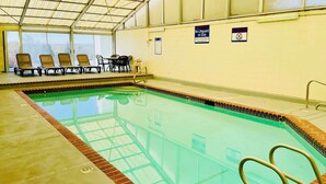 An indoor swimming pool with clear water, a tiled edge, and a lifeguard sign indicating no lifeguard on duty.