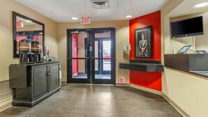 A hotel lobby with a reception desk, a coffee machine, and an exit sign.