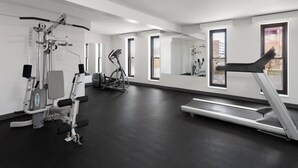 A modern gym with various exercise equipment, large windows, and a clean, minimalist design.