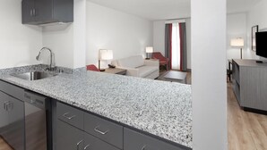 A modern kitchen with granite countertops, a built-in dishwasher, and a grey cabinet.