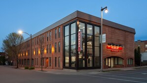 A brick building with large windows and a sign for 'Ramada by Wyndham'.