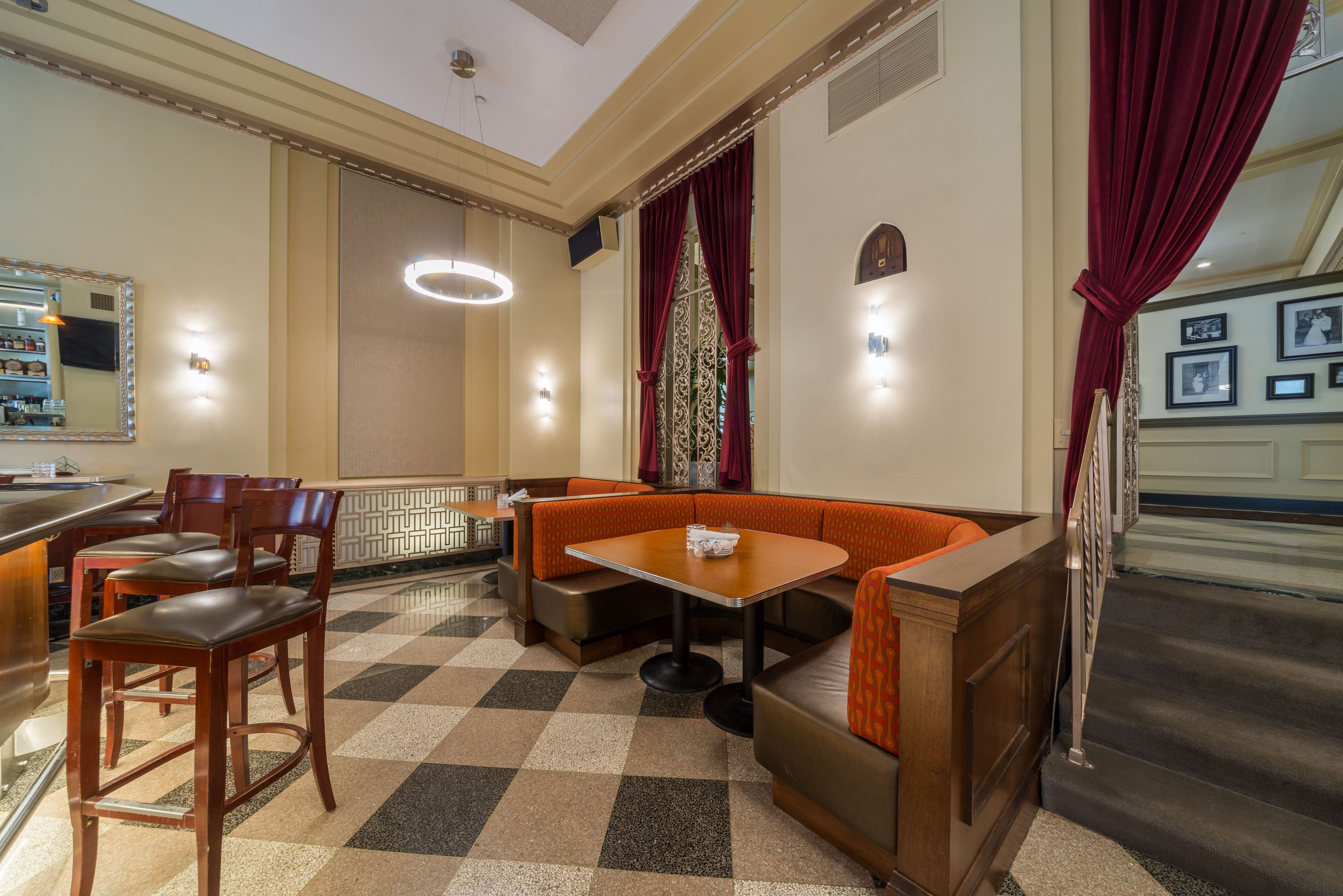 Un restaurante con piso a cuadros, muebles de madera y cortinas rojas.