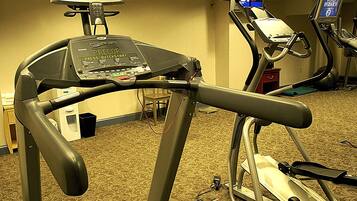 Ein Laufband und ein stationäres Fahrrad, beide mit digitaler Anzeige, in einem Hotelzimmer.