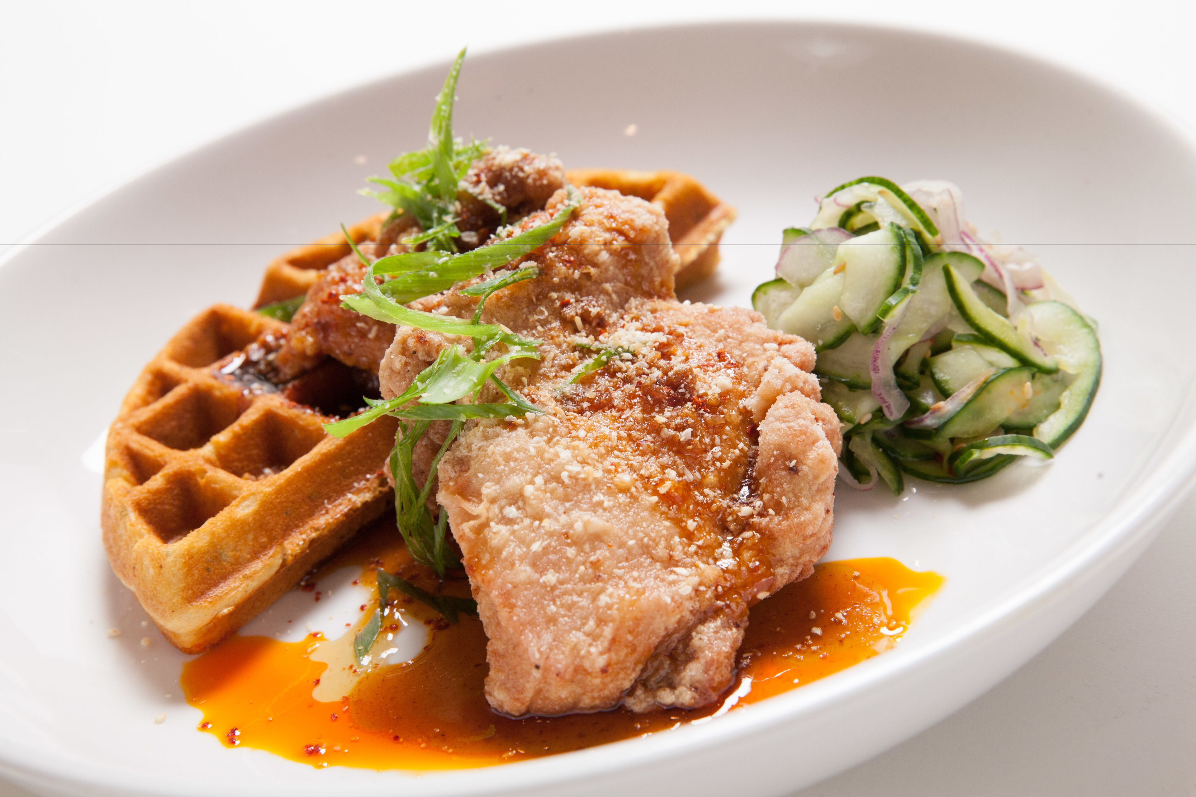 Une assiette comprenant un gaufre, du poulet frit et une salade d’accompagnement.