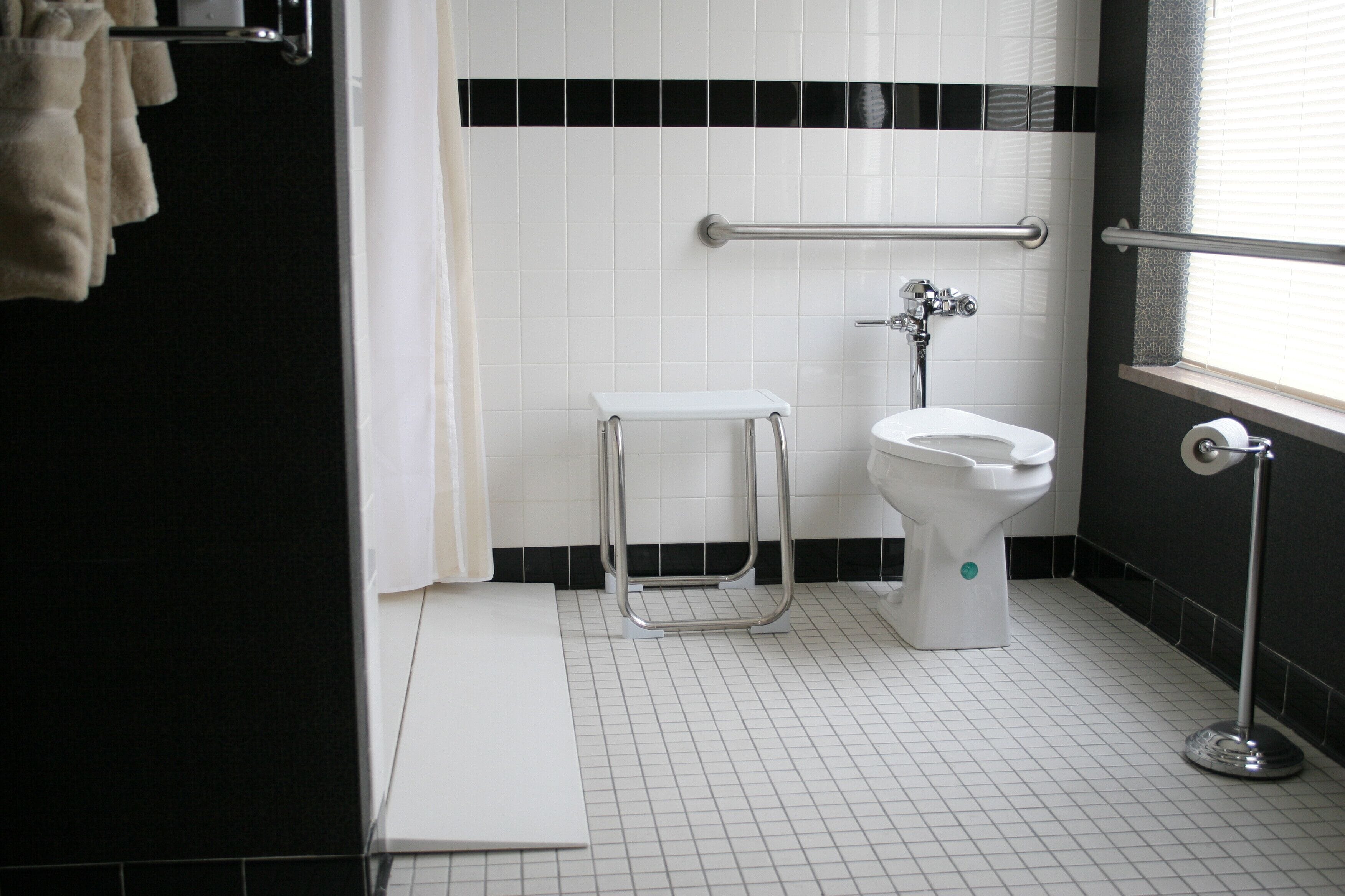 A bathroom with a white toilet, a white sink, a grab bar, and a towel rack.