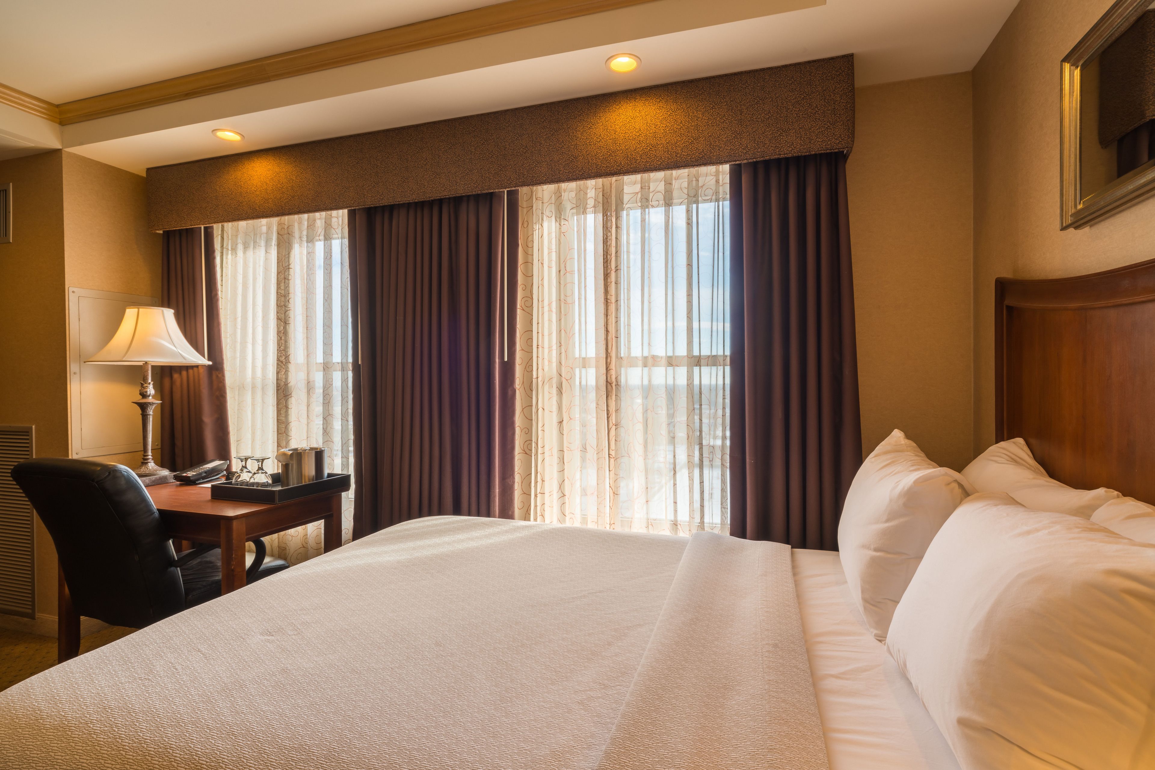 Ein Hotelzimmer mit einem großen Bett, einem Schreibtisch mit Lampe und einem Sessel.
