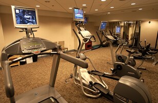 Gimnasio de hotel con cintas de correr, bicicletas estáticas y equipo de ejercicio.