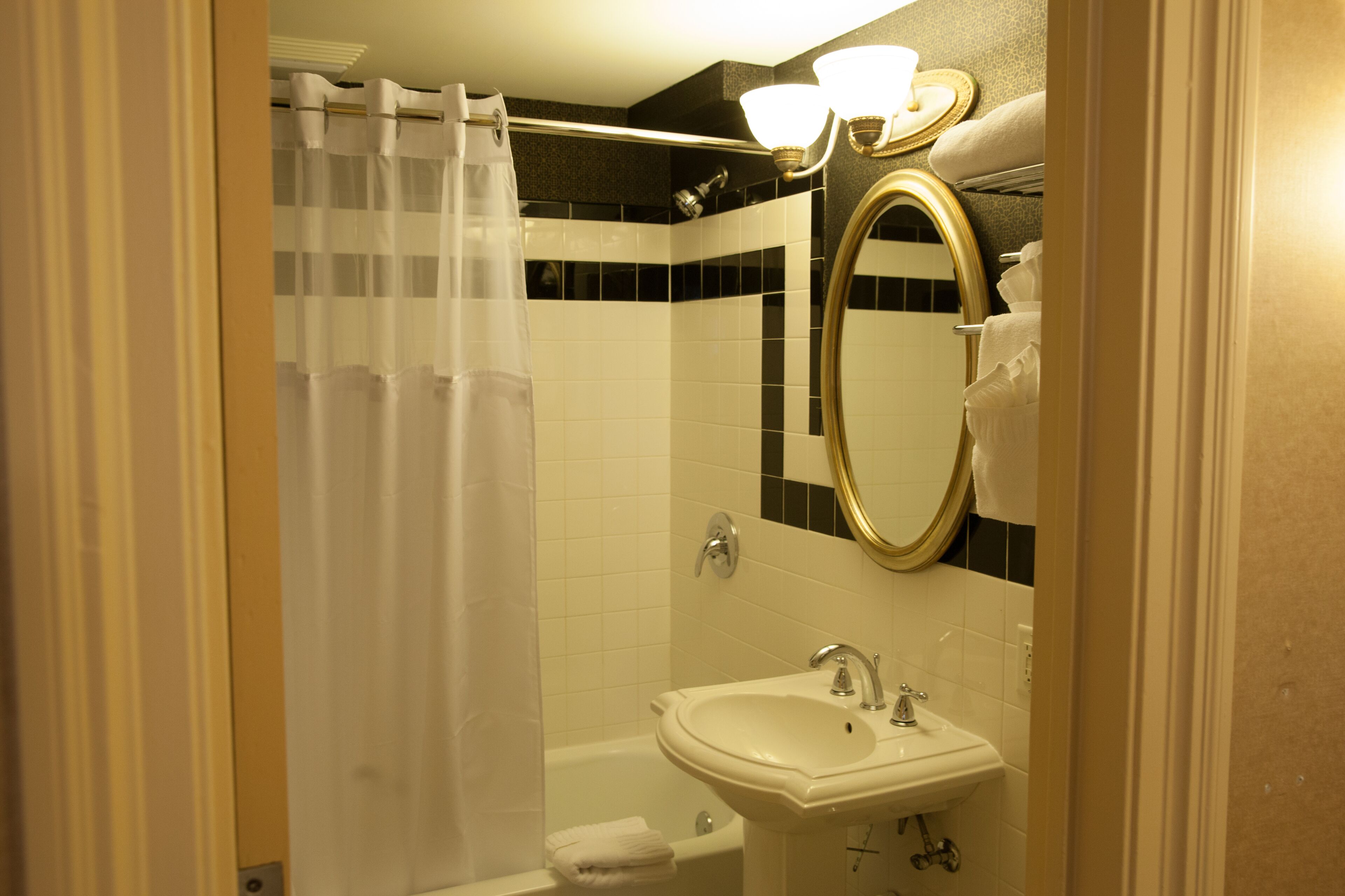 Ein Badezimmer mit Duschvorhang, Waschbecken, Spiegel und Handtuchhalter.