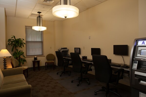 A conference room with a large table, multiple chairs, a desk with a computer, a printer, a plant, and a lamp. - Ambassador Hotel Milwaukee, Trademark Collection by Wyndham (Milwaukee)