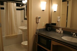 Un bagno con doccia, WC, lavandino e un asciugacapelli sul ripiano.