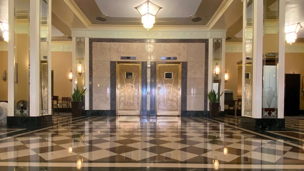 A lobby with a checkered floor, two elevators, and a chandelier. - Ambassador Hotel Milwaukee, Trademark Collection by Wyndham (Milwaukee)