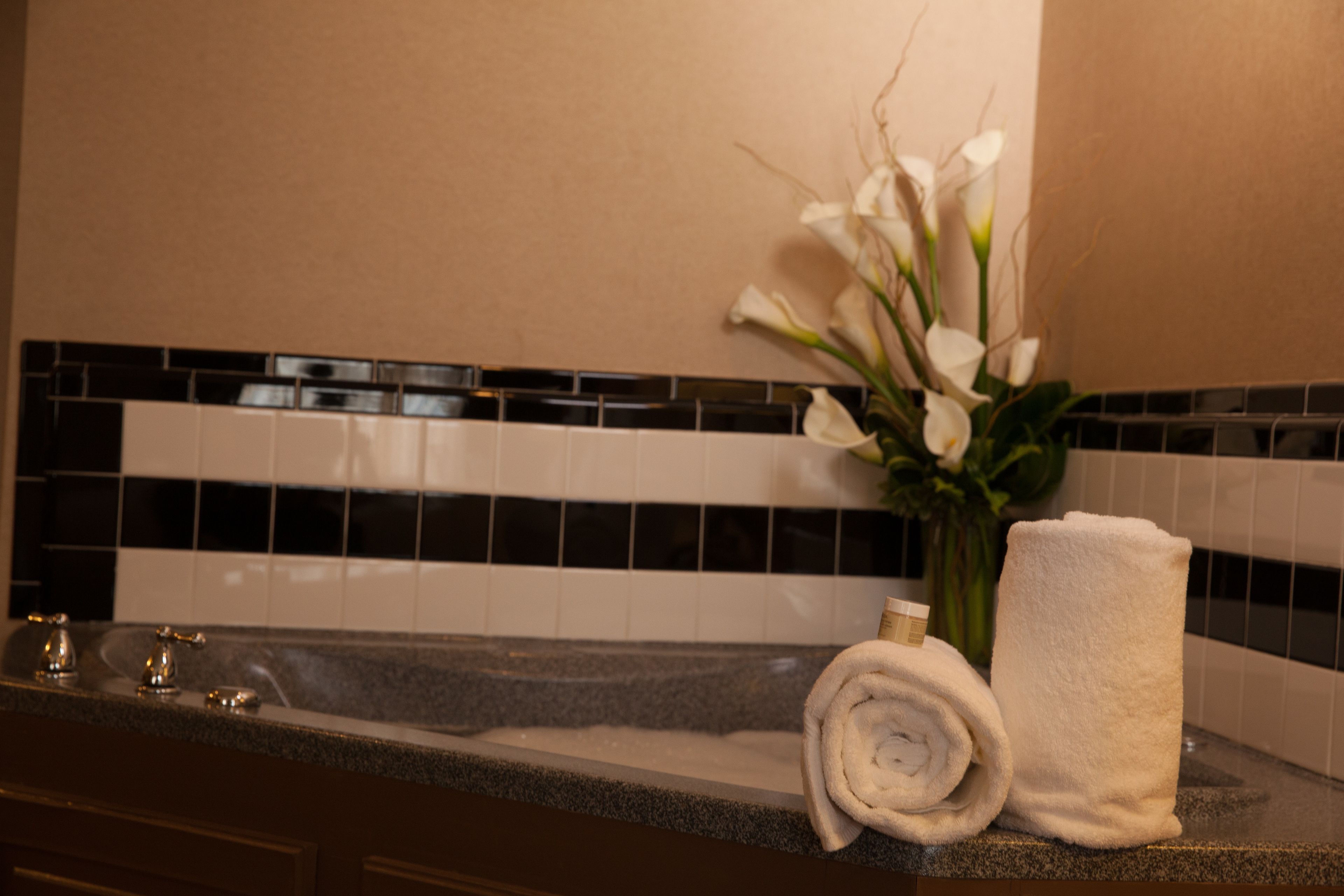 A bathroom with a sink, a towel, and a vase of flowers.