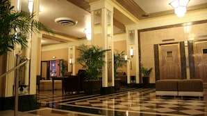 A lobby with a checkered floor, a staircase, and a reception desk. - Ambassador Hotel Milwaukee, Trademark Collection by Wyndham (Milwaukee)