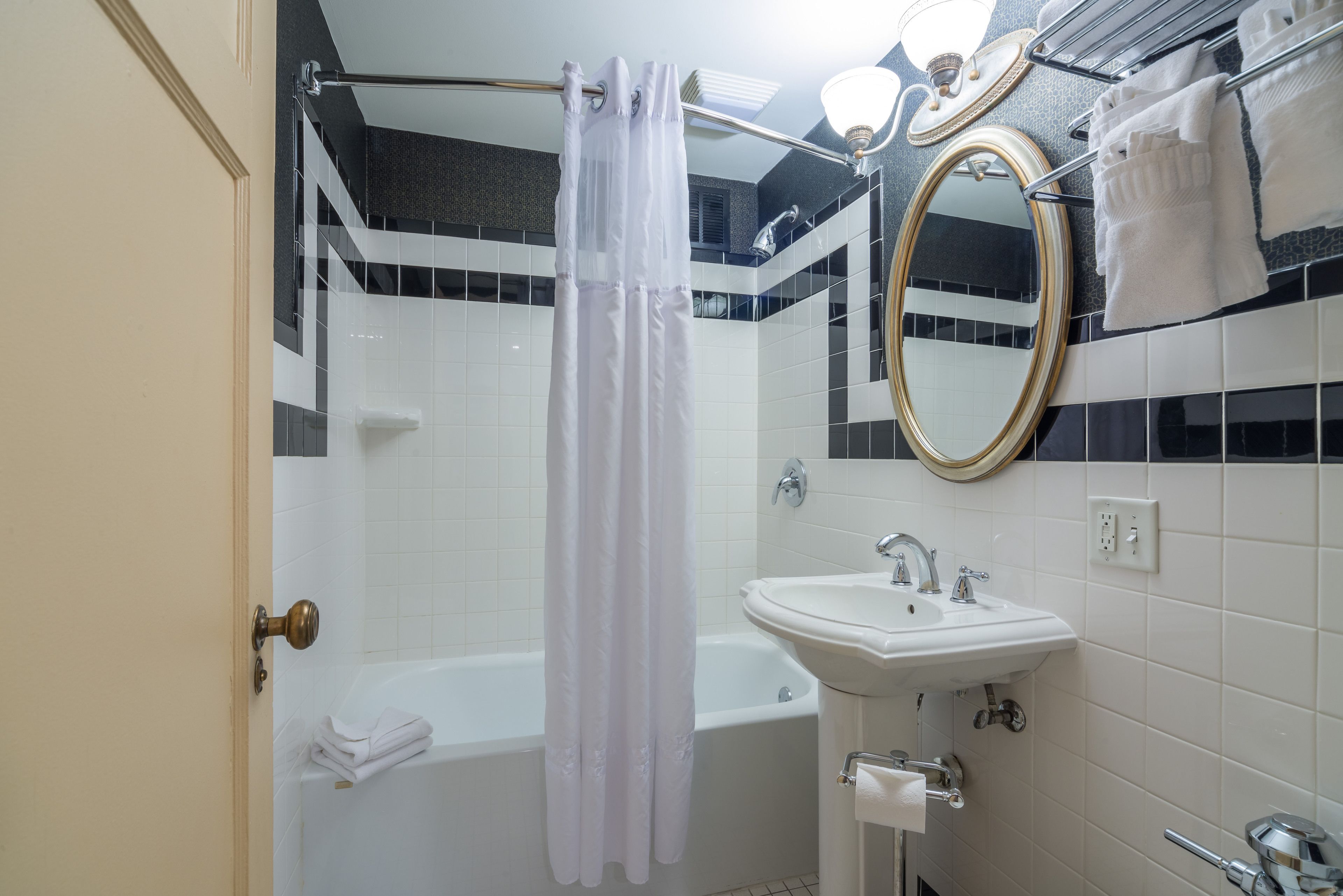 Une salle de bain avec une baignoire, un lavabo, un miroir et un rideau de douche.