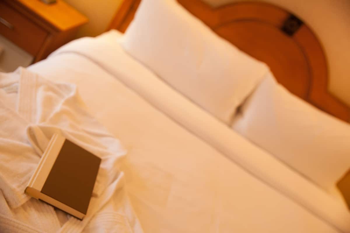 A bed with white linens and a book on it.