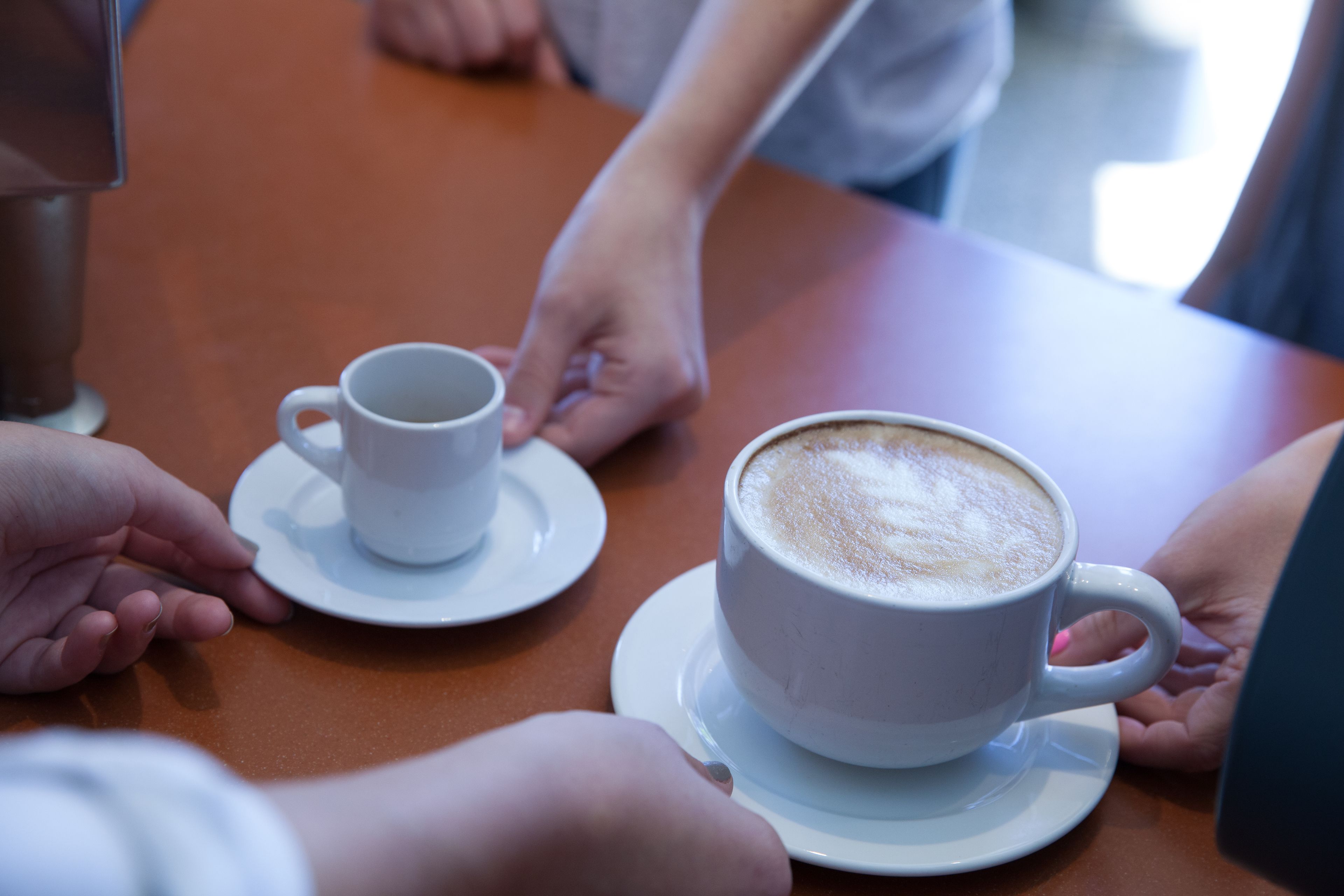 Uma mesa com duas xícaras de café brancas, uma com pires e outra sem.