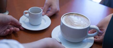 Uma mesa com duas xícaras de café brancas, uma com pires e outra sem.