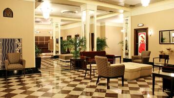 A lobby with a checkered floor, seating areas, and a large mirror.