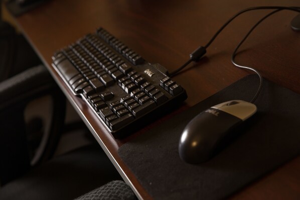 Una scrivania in legno con una tastiera nera e un mouse collegato tramite cavo.