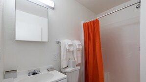Un baño con lavamanos, inodoro y cortina de ducha blancos.
