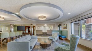 A modern living room with a sectional sofa, a round coffee table, and patterned armchairs.