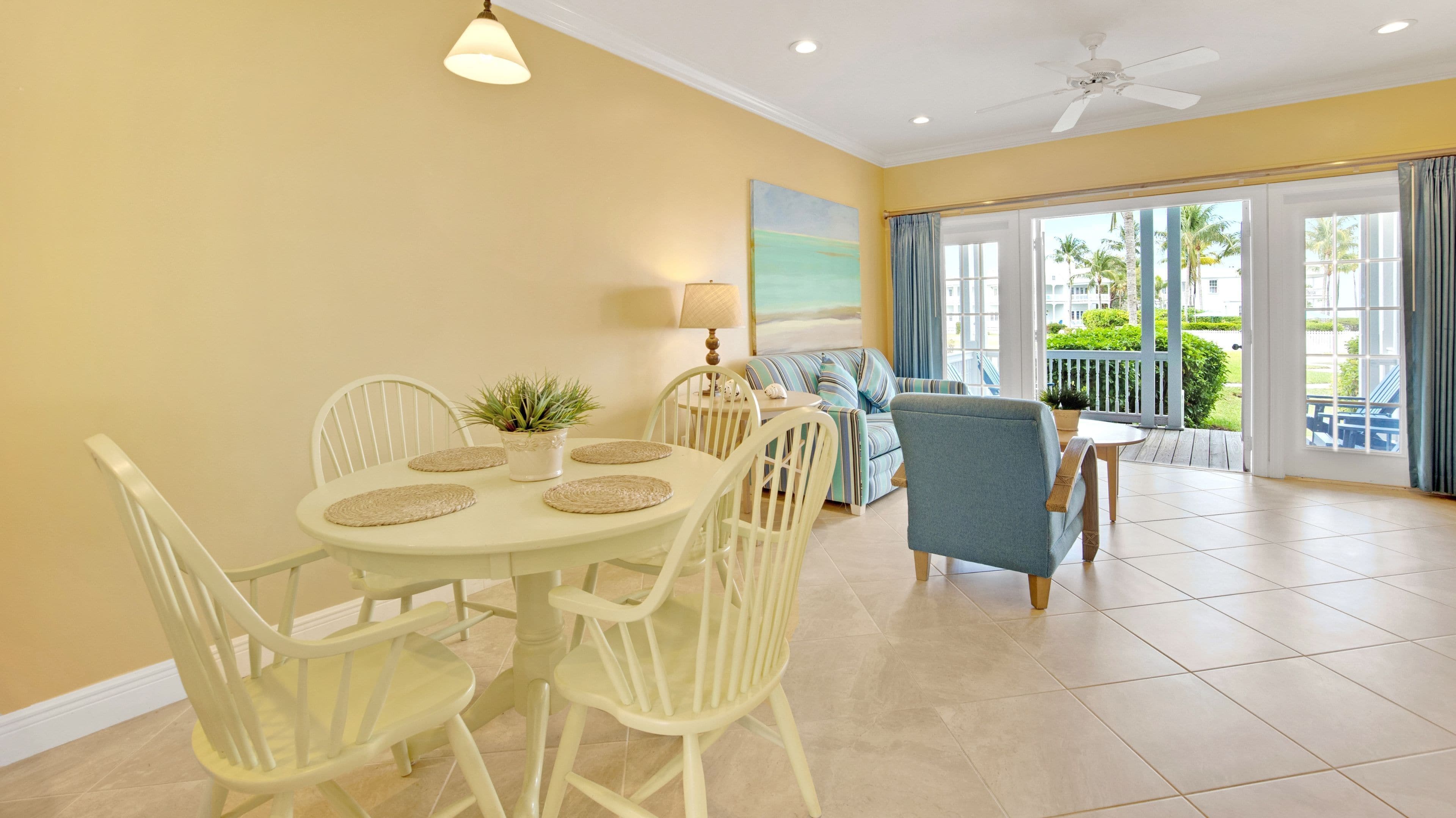 A bright room with a dining table, chairs, a sofa, and a view of the outdoors.