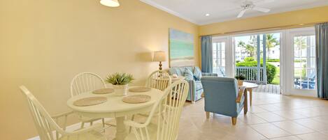 A bright room with a dining table, chairs, a sofa, and a view of the outdoors.