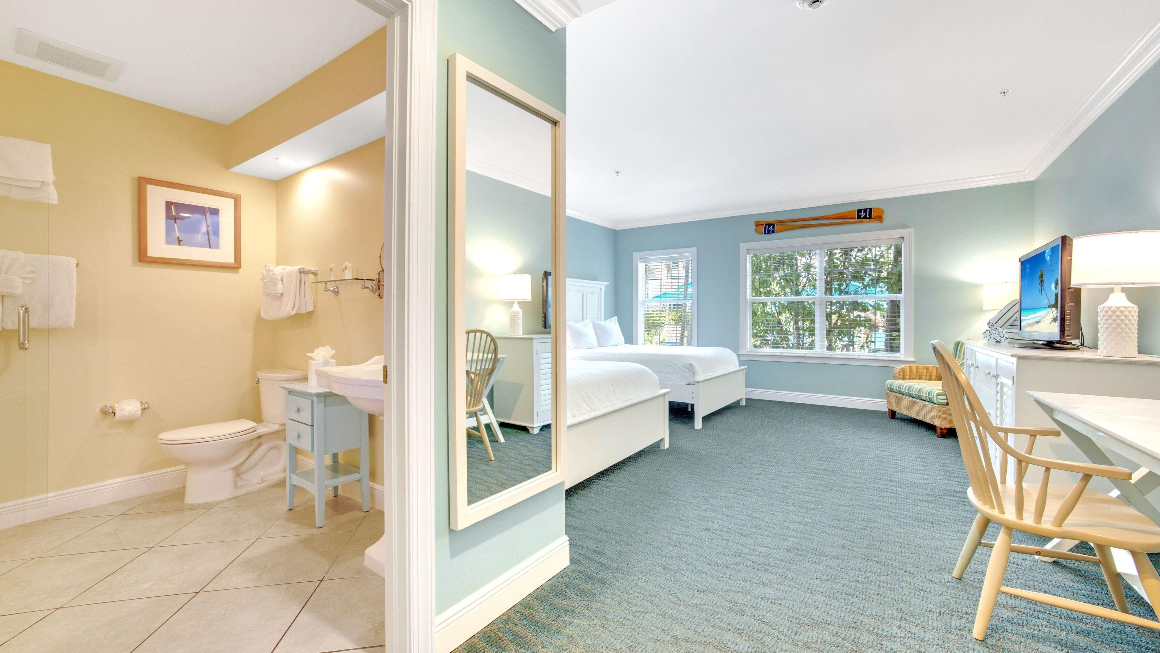A hotel room with a bathroom, a bed, a desk, and a chair.