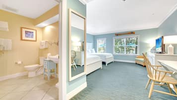 A hotel room with a bathroom, a bed, a desk, and a chair.