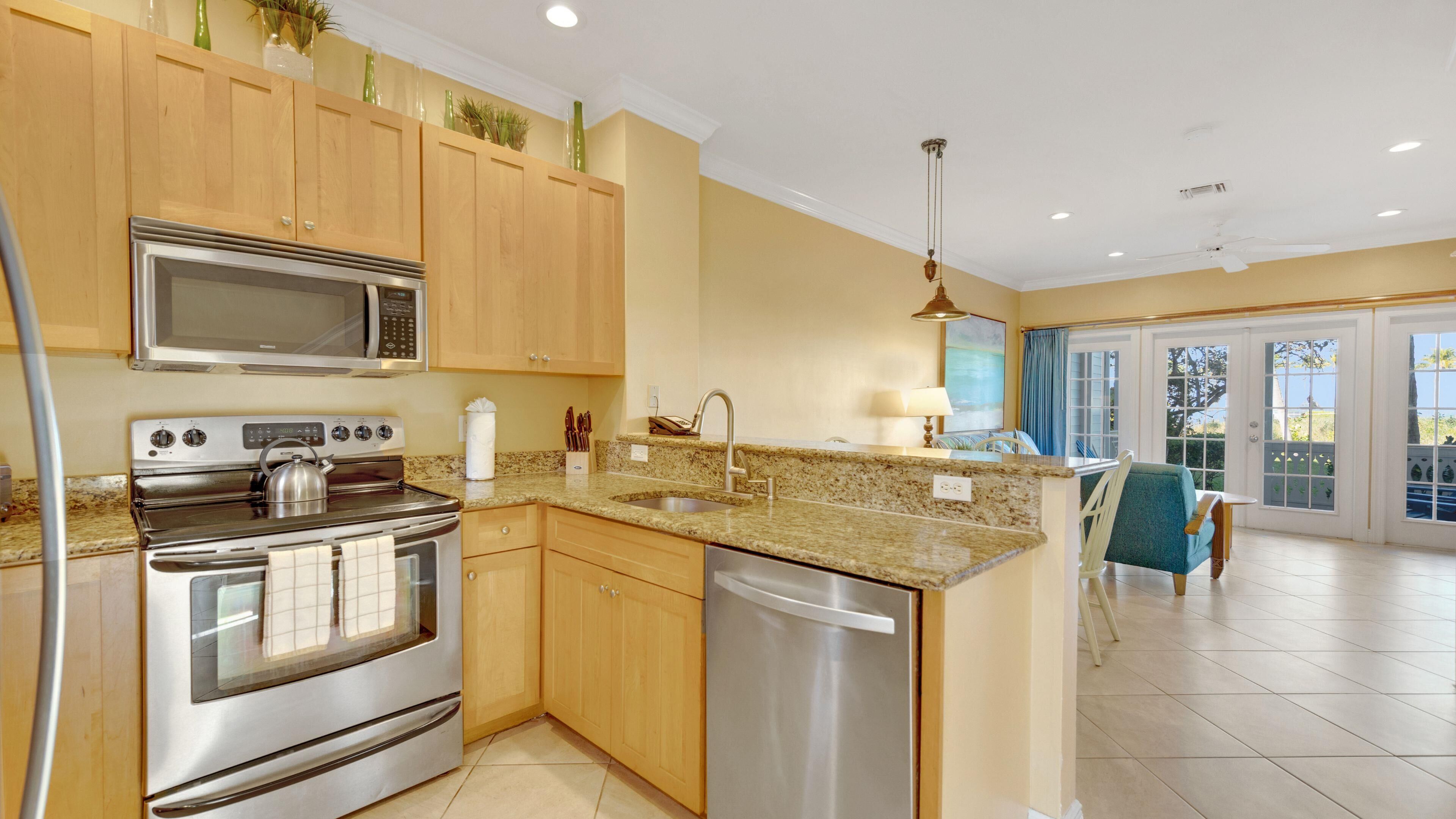 A modern kitchen with stainless steel appliances, wooden cabinets, and a granite countertop.