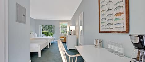 Een hotelkamer met een bed, een bureau, een stoel, een koffieapparaat en een lijst met een afbeelding van een vis.