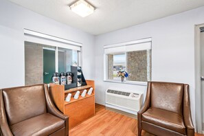 Una habitación con dos sillones de cuero, una estación de café, un ventanal con pared de piedra y un equipo de aire acondicionado.