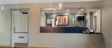 A reception area with a glass partition, a reception desk, a door, and a small window.