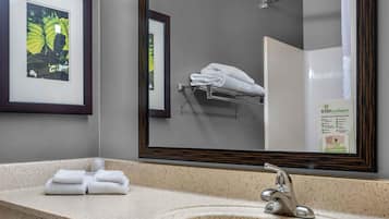 Un baño con un espejo grande, un lavabo y un perchero para toallas.