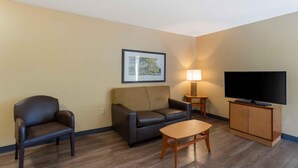 A living room with a sofa, armchair, coffee table, TV, and lamp. - Extended Stay America Suites Philadelphia Airport Bartram Av (Philadelphia)