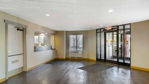 A spacious lobby with a dark wooden floor, a glass door entrance, and a wall-mounted air conditioning unit. - Extended Stay America Suites Philadelphia Airport Bartram Av (Philadelphia)