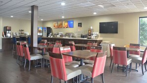 A cafeteria with multiple tables and chairs, a coffee station, and a television mounted on the wall. - Comfort Inn & Suites Maumee - Toledo (I80-90) (Maumee)