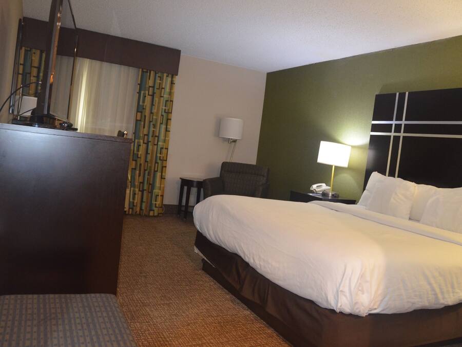 Une chambre d’hôtel équipée d’un lit, d’un bureau, d’une chaise, d’une lampe et d’un téléphone.