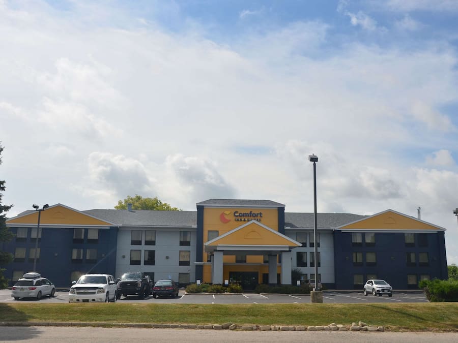A Comfort Inn with a two-story building, a parking lot with several cars, and a clear sky.
