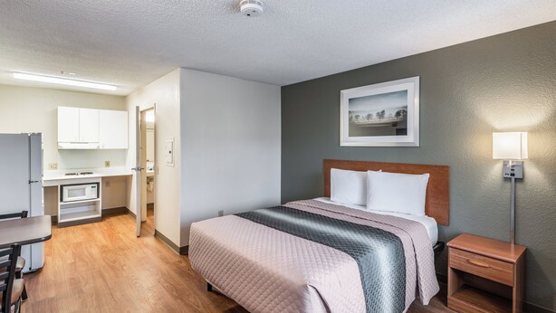 Une chambre d’hôtel avec un lit, une table de chevet et vue sur le couloir.